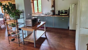 A kitchen with wooden beams, a stainless steel refrigerator, a microwave, and a sink. - Gîte Le Rucan Atypical house in the Pyrenees Commingeoises (Montastruc-de-Salies)