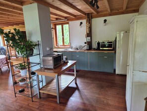 Eine Küche mit Holzbalken, einem Edelstahl-Kühlschrank, einer Mikrowelle und einem Spülbecken.