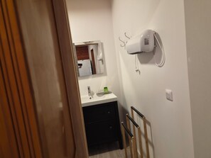 A bathroom with a white sink, a mirror, a towel rack, and a white wall-mounted heater. - Gîte Le Rucan Atypical house in the Pyrenees Commingeoises (Montastruc-de-Salies)