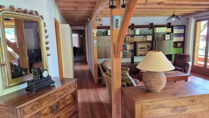 A wooden interior with a large mirror, a wooden table with a lamp, and a bookshelf filled with books. - Gîte Le Rucan Atypical house in the Pyrenees Commingeoises (Montastruc-de-Salies)