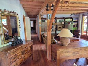 Ein Holzinterieur mit einem großen Spiegel, einem Holztisch mit einer Lampe und einem Bücherregal voller Bücher.