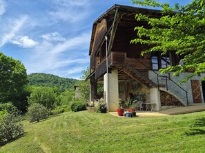Ein rustikales Holzhaus mit Stein Fundament, einer Veranda und Blick auf eine Hügel landschaft.