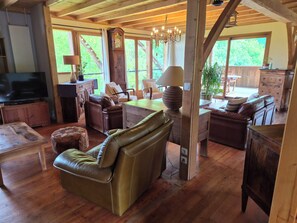 A spacious living area with a wooden ceiling, leather furniture, a large clock, and a chandelier. - Gîte Le Rucan: A Unique House in the Commingeoises Pyrenees (Montastruc-de-Salies)