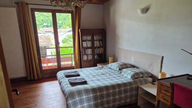 A bedroom with a bed, a wooden desk, a bookshelf, and a view through a door. - Gîte Le Rucan Atypical house in the Pyrenees Commingeoises (Montastruc-de-Salies)
