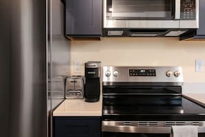Una cocina moderna con electrodomésticos de acero inoxidable, incluyendo un microondas, horno y cafetera.