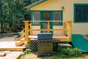 A wooden deck with a grill and a small outdoor kitchen area.