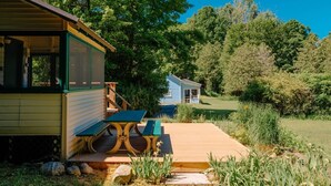 Una baita con una veranda, un tavolo da picnic e un piccolo edificio sullo sfondo.