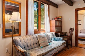 A cozy room with a sofa, a lamp, a bookshelf, and a window with curtains.