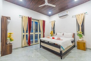 A bedroom with a bed, curtains, a ceiling fan, an air conditioning unit, and a small cabinet. - Sun Set Villa (Mawal)