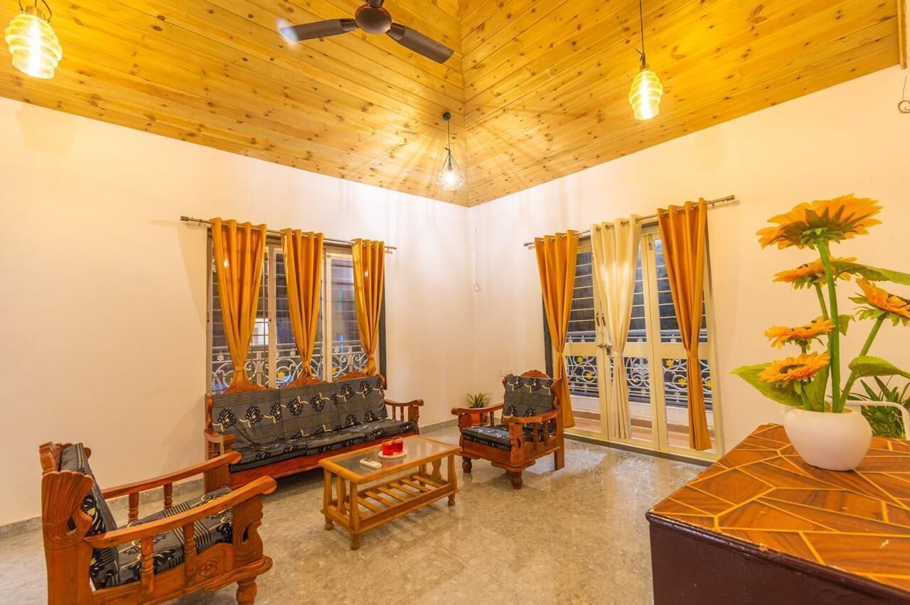 A room with a wooden ceiling, a sofa set, a coffee table, and a decorative vase with flowers.
