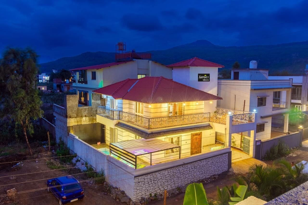 A multi-story residential building with balconies, a swimming pool, and a mountain backdrop.