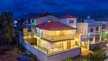 A multi-story residential building with balconies, a swimming pool, and a mountain backdrop.