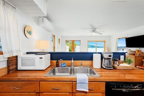 A kitchen with a microwave, coffee maker, and a sink.