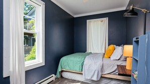 Un dormitorio con cama, ventana, mesita de noche y lámpara.