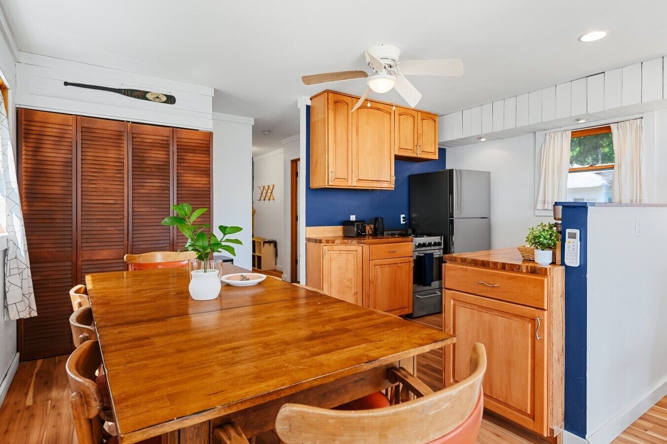 Una cocina moderna con armarios de madera, una mesa de comedor y un ventilador de techo.