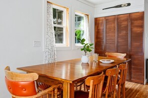 Ein Essbereich mit Holztisch, Stühlen, einem Blumentopf und einem Fenster mit Vorhängen.