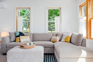 A modern living room with a grey sectional sofa, a round coffee table, and a striped rug.