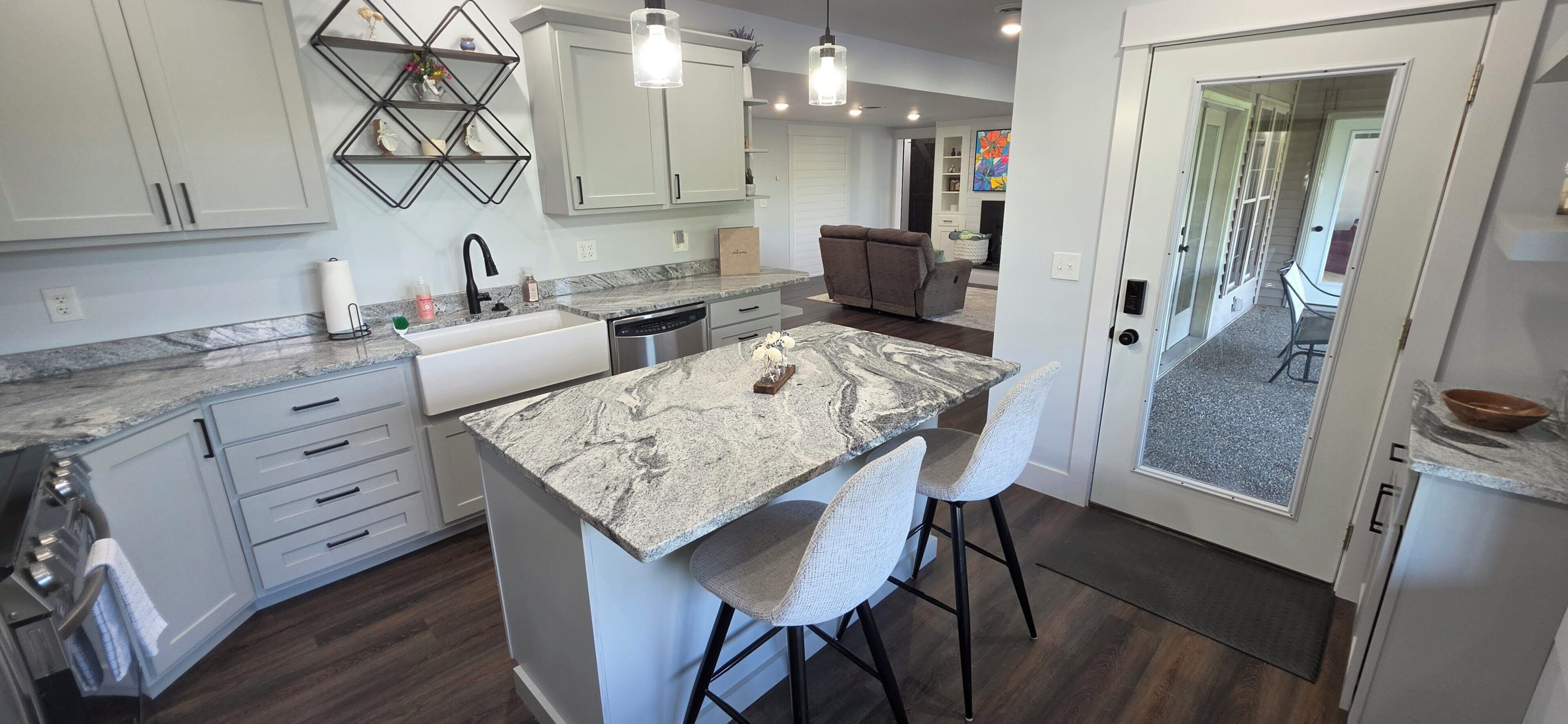 A modern kitchen with a central island, bar stools, and a dining area with a sofa.