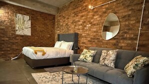Ein modernes Schlafzimmer mit einem Bett, einem Sofa, einem runden Couchtisch und einem Teppich.
