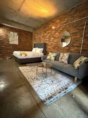 Ein modernes Schlafzimmer mit einem Bett, einem Sofa, einem runden Couchtisch und einem Teppich.