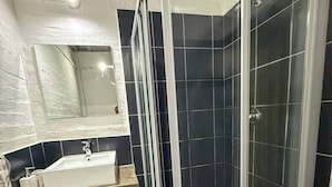 Ein Badezimmer mit Duschkabine, Waschbecken und Spiegel.