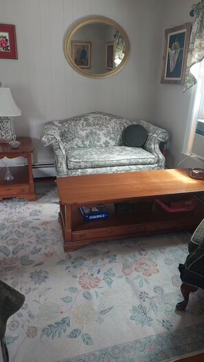 A living room with a floral-patterned sofa, a wooden coffee table, and a patterned rug. - Barr Street Retreat Charming 2BR Near Downtown Salem (Salem)