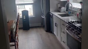 Eine Küche mit Kühlschrank, Herd, Spüle und einem Fenster mit Jalousien.