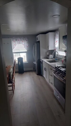 A kitchen with a refrigerator, stove, sink, and window with blinds. - Barr Street Retreat Charming 2BR Near Downtown Salem (Salem)