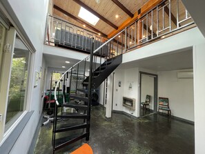 Un intérieur spacieux avec une mezzanine, un escalier et un espace dédié à la salle de sport.