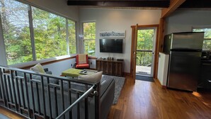 A modern kitchen with a built-in refrigerator, a dining area with a bench, and a large window offering a view of trees. - Retromoderninthewoods steps from the best trails in the Linville gorge wildernes (Newland)