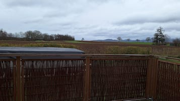 Ein Holzzaun mit Blick auf ein Feld und entfernte Bäume.