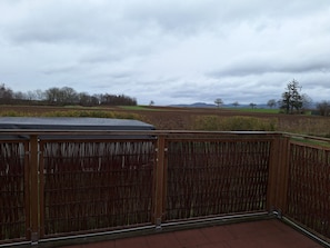 A wooden fence with a view of a field and distant trees.