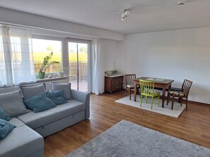 Ein modernes Wohnzimmer mit grauem Sofa, Esstisch aus Holz und Stühlen.