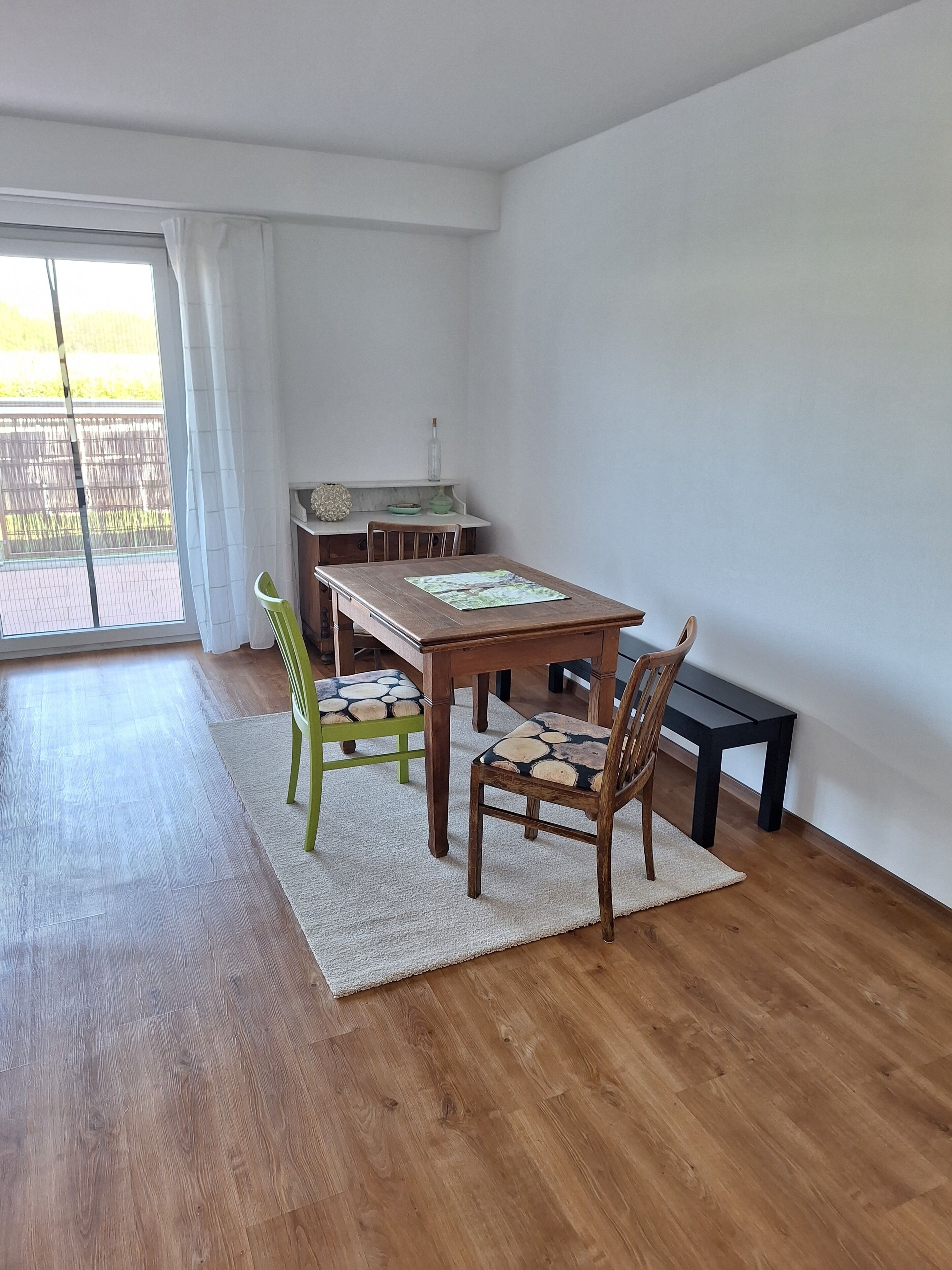 Un comedor con una mesa de madera, dos sillas y un banco.