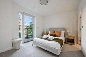 Ein Schlafzimmer mit einem großen Bett, zwei Nachttischen, einem Schrank und einem Fenster sowie einer Tür.