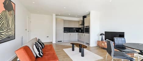 A modern living room with a sofa, coffee table, and dining area.