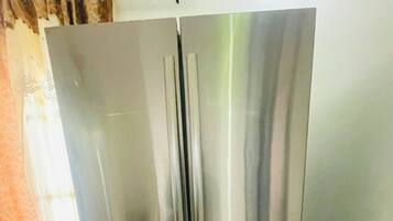 Ein Edelstahl-Kühlschrank in einer Küche mit gefliestem Boden und einem Vorhang.