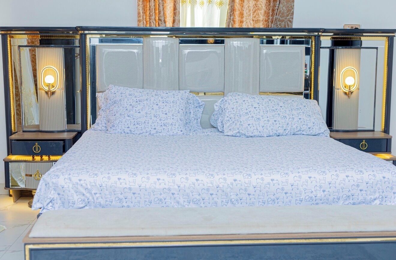 A bed with a patterned bedspread, two bedside tables with lamps, and a mirror above the bed.
