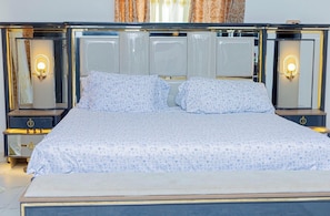 A bed with a patterned bedspread, two bedside tables with lamps, and a mirror above the bed.