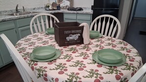 A dining table with a floral tablecloth, green plates, and a 'Fresh Groceries' sign. - Historical Main Street Studio in Charming La Crosse (La Crosse)