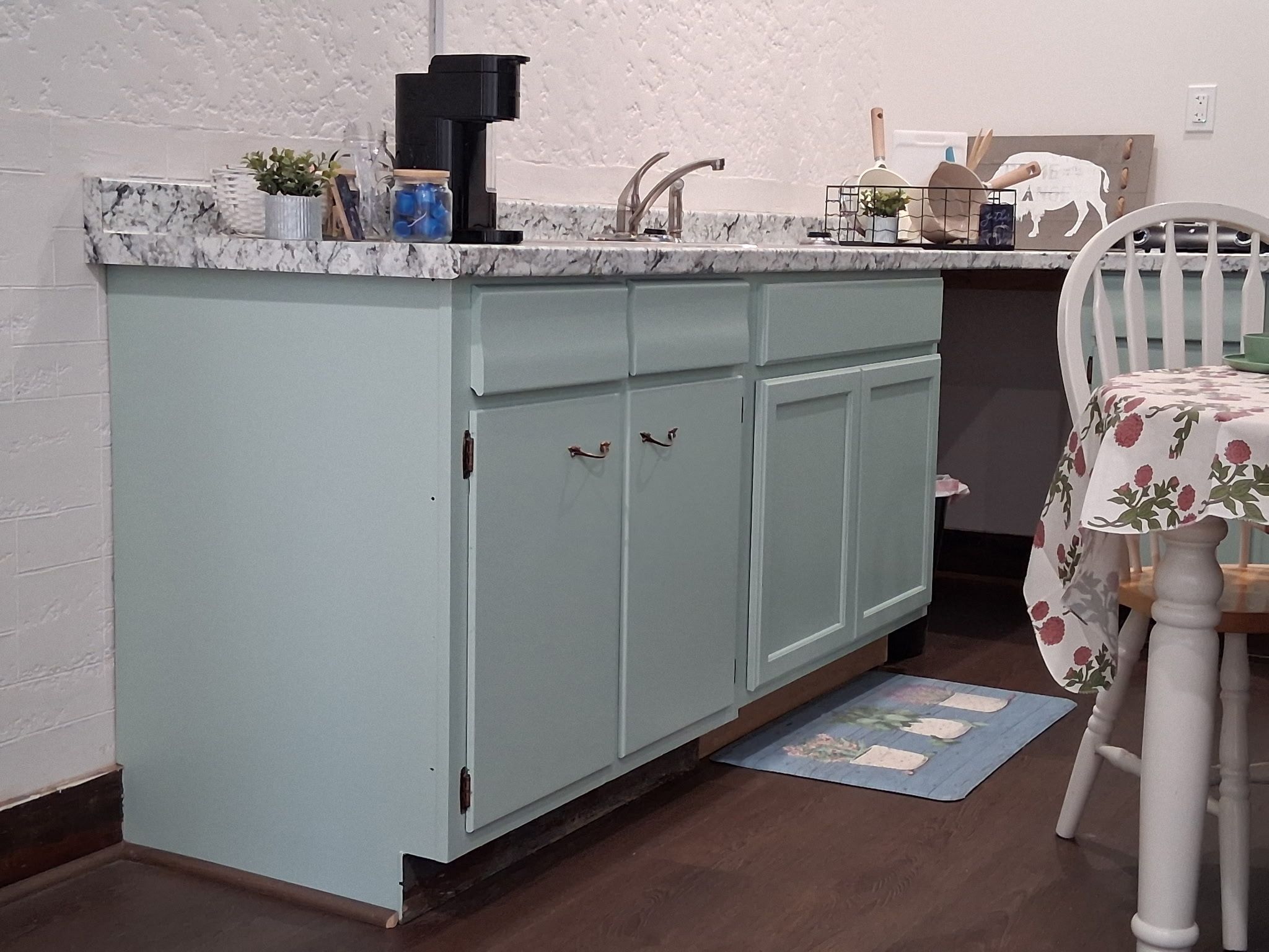 Eine Küche mit einer hellblauen Arbeitsplatte, einer Kaffeemaschine und einem Spülbecken.
