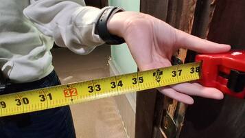 A person measuring a door with a yellow measuring tape.
