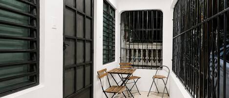 A corridor with a tiled floor, a door with a black metal gate, and a table with chairs.