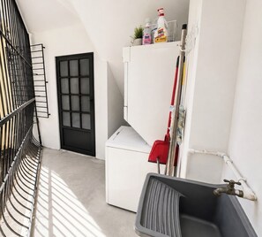 A laundry area with a washing machine, a drying rack, and cleaning supplies. - ADA access • cozy • oceanfront 
A relaxing beach stay full of comfort & sunsets. (Tamarindo)