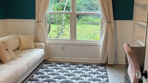 A room with a sofa, a patterned rug, a desk with a chair, and a window with curtains. - Peaceful Vintage Charm in North Asheville (Asheville)