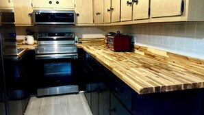 A kitchen with stainless steel appliances, wooden cabinets, and a wooden countertop. - Peaceful Vintage Charm in North Asheville (Asheville)
