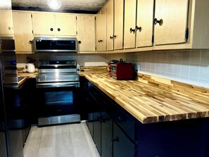 Eine Küche mit Edelstahlgeräten, Holzschränken und einer Holzarbeitsplatte.