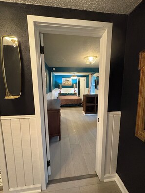A hallway leading to a bedroom with a bed, bedside table, and a nightstand. - Peaceful Vintage Charm in North Asheville (Asheville)