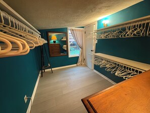 Ein Korridor mit Holzboden, einem Spiegel, einer Lampe und einer zur Balkon führenden Tür.