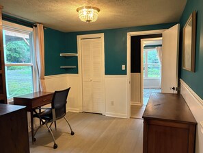 A room with teal walls, a wooden desk, a chair, a white closet, and a chandelier. - Peaceful Vintage Charm in North Asheville (Asheville)